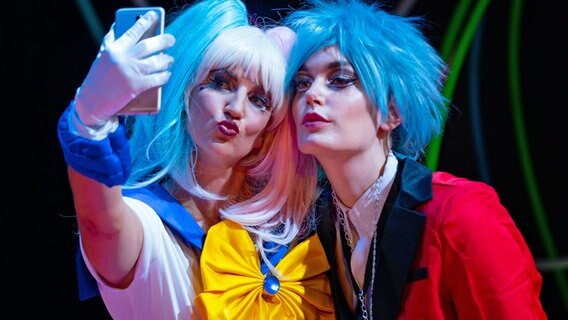 Zwei Opernsänger in bunten Kleidern und mit blauen Haaren machen ein Selfie. © Inken Rahardt/ Opernloft Foto: Inken Rahardt