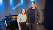 Eine Frau mit heller gestreifter Bluse steht neben einem großen Mann, der dunkel gekleidet ist. Beide stehen vor einem schwarzen Flügel. © Ekaterina Shurygina / NDR Foto: Ekaterina Shurygina / NDR