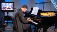 Ein Mann, der dunkel gekleidet ist, sitzt vor einem schwarzen Flügel. Seine Hände liegen auf den Tasten und er ist vertieft in die Musik. © Ekaterina Shurygina / NDR Foto: Ekaterina Shurygina / NDR
