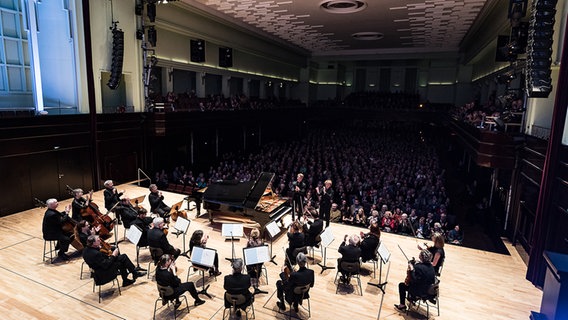 Mehrere Streicher sitzen um ein Klavier gruppiert auf einer Bühne © Peter Hundert 