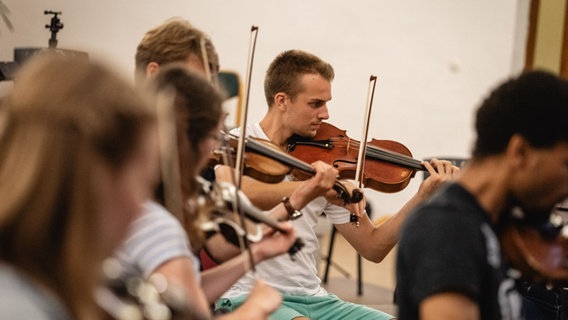 Ein junger Mann spielt zusammen mit anderen Musizierenden Geige. © Florian Semmler Foto: Florian Semmler