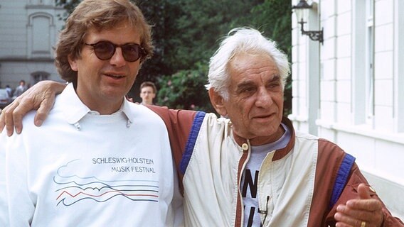 Justus Frantz  im SHMF-T-Shirt posiert mit Leonard Bernstein vor Schloss Salzau (1987). © Picture Alliance/dpa 