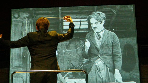 Dirigent vor Leinwand mit Charlie Chaplin © Axel Nickolaus / fotonick.de Foto: Axel Nickolaus