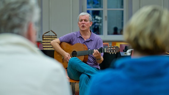 Mann mit Gitarre beim Singen im Stuhlkreis © picture alliance / dpa | Daniel Karmann Foto: Daniel Karmann