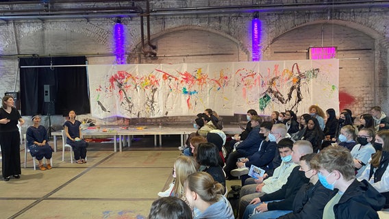 Sophie Steiner, die japanischen Malerinnen Yuka Shinozaki und Misaki Ouchi und das Publikum vor dem Werk der Malerinnen beim Projekt SoundColours in Lübeck. © Linda Ebener / NDR Foto: Linda Ebener