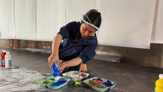 Die Malerin Yuka Shinozaki füllt kleine Schüsseln mit Farben auf. © Linda Ebener / NDR Foto: Linda Ebener