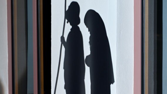 Zwei Schatten auf einer Mauer von Kindern, die als Maria und Josef die Weihnachtsgeschichte nachspielen. © picture alliance/dpa | Felix Kästle 