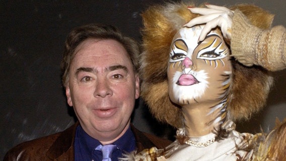 Der englische Komponist Andrew Lloyd-Webber im Profil, dahinter eine Maske aus dem berühmten Musical "Das Phantom der Oper" © dpa +++ dpa-Bildfunk +++ Foto: Jens Kalaene