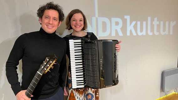 Links steht ein Mann mit lockigem Haar und einer Gitarre in der Hand und rechts neben ihm steht eine Frau, sie hält ein Akkordeon. © Claus Röck / NDR Foto: Claus Röck