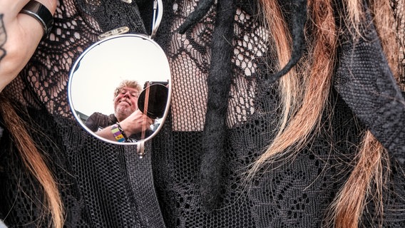 Fotograf Benjamin Hüllenkremer spiegelt sich in dem Glas einer Sonnenbrille beim Gothic-Musikfestival M'era Luna 2023. © NDR Foto: Benjamin Hüllenkremer