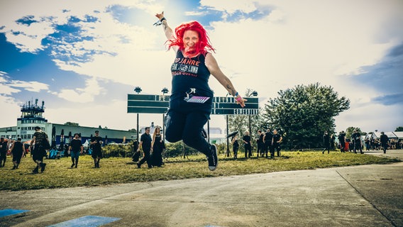 Eine Frau mit roten Haaren beim Festival M'era Luna 2023 springt in die Höhe © NDR Foto: Benjamin Hüllenkremer