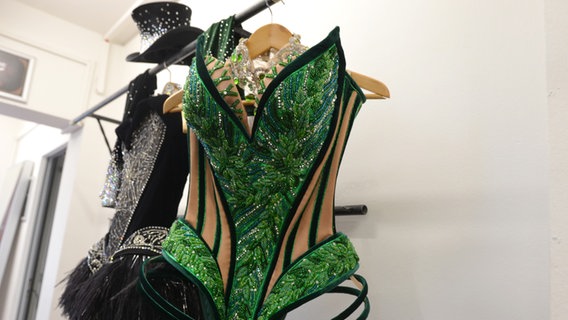 Ein grünes Corsage-Kostüm und ein schwarzes Outfit und Zylinder sind Teil der  Show für das Musical "Moulin Rouge" © NDR Foto: Patricia Batlle