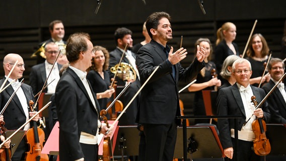 Die Münchner Philharmoniker und Dirigent Lahav Shani stehen auf der Bühne. © Tobais Hase 
