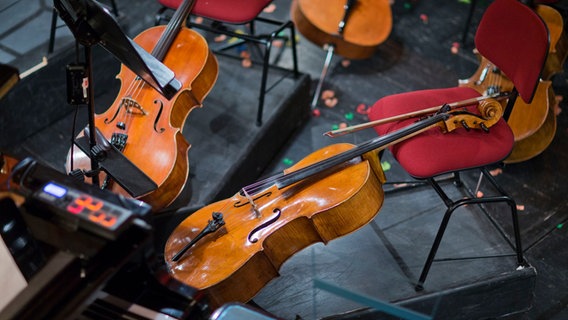 Mehrere Violinen, Stühle und Notenständer in einem Orchestergraben. © picture alliance / dpa Foto: Jens Büttner