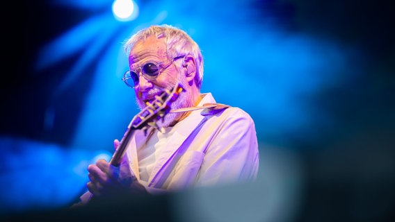 Ein Mann im hellen Anzug und mit Sonnenbrille spielt Gitarre © picture alliance/dpa Foto: Christoph Soeder