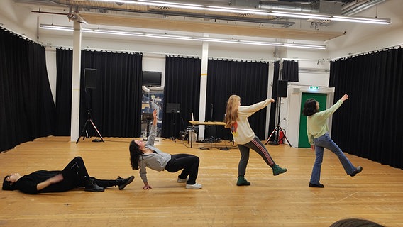 In einem Theaterprobenraum liegt eine Frau auf dem Boden (links), eine Frau stützt sich zum Aufstehen hoch, zwei weitere Frauen gehen. © NDR / Svenja Estner Foto: Svenja Estner