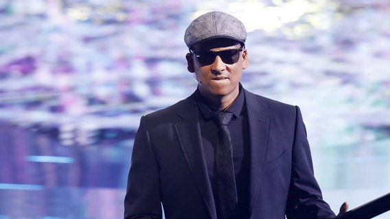 A man in a black suit, sunglasses and a hat is on stage.  © IMAGO / Future Image Photo: C. Hardt