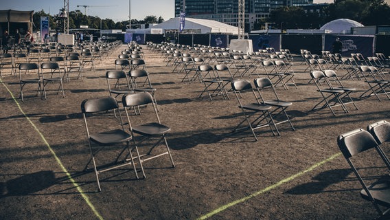 Dutzende von nicht besetzten Klappstühlen stehen auf dem Festivalgelände. © NDR Foto: Benjamin Hüllenkremer