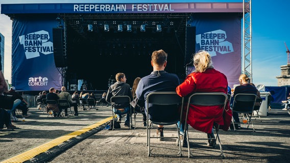 Menschen sitzen auf Klappstühlen vor der Bühne. © NDR Foto: Benjamin Hüllenkremer