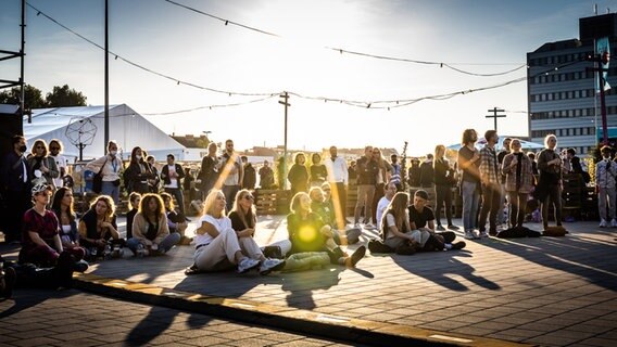 Blick ins Publikum beim Reeperbahn Festival auf dem Heiligengeistfeld in Hamburg: Die Leute stehen und sitzen in Grüppchen in der Sonne. © Julian Rausche Foto: Julian Rausche
