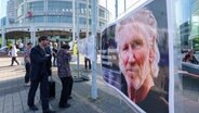 Menschen betrachten ein Plakat von Musiklegende Roger Waters © dpa Foto: Andreas Arnold