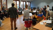 Im Vordergrund stehen einige Musiker*innen, im Hintergrund einige Jugendliche © NDR Foto: Ulla Vaasen