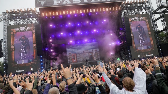 Fans recken vor der Bühne "Faster Stage" des Wacken Open Air 2023 ihre Finger hoch. © picture alliance / dpa Foto: Christian Charisius