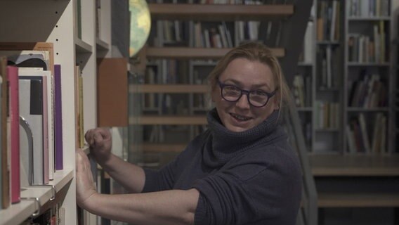Katharina Hanschel steht an einem Bücherregal. Im Hintergrund sieht man noch mehr Bücher ihres Antiquariats. © Juliane Voigt / NDR Foto: Juliane Voigt