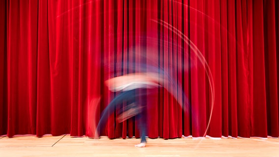 Ein Darsteller vor einem roten Vorhang.
Rote, schwach beleuchtete Stuhlreihen vor einer beleuchteten Kinoleinwand © Marqs / Photocase Foto: Marqs
