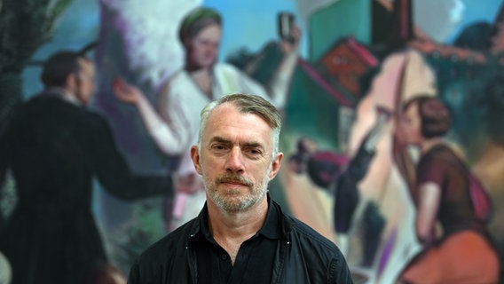 Der Maler Neo Rauch steht in der Galerie "Eigen + Art" vor seiner Arbeit "Die Wurzel". © Picture Alliance / Hendrik Schmidt Foto: Hendrik Schmidt