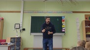 Ein Friesischlehrer steht vor einer Tafel und spricht in die Klasse © NDR.de/ Peer-Axel Kroeske Foto: Peer-Axel Kroeske