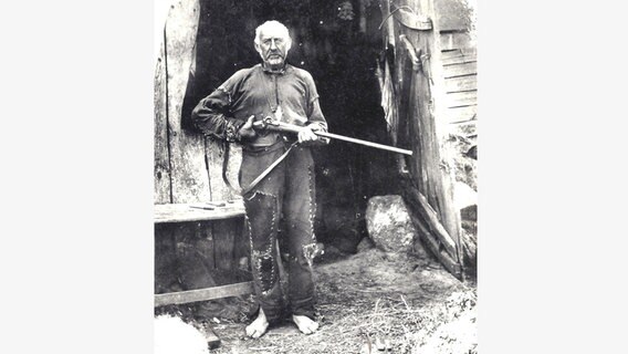 Ein nostalgisches Foto zeigt einen Mann in zerschlissener Kleidung mit einer Flinte in der Hand. © Orts- und Heimatverein Ganderkesee 