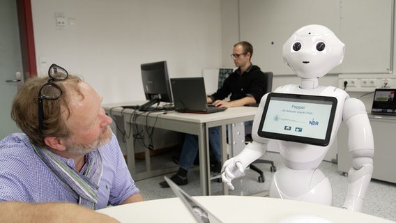 NDR-Reporter Lornz Lorenzen spricht mit Roboter Pepper. © NDR Foto: Jorrit Groth
