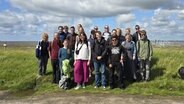 Die Teilnehmenden des Minderheiten-Austausches stehen an der Nordsee und lächeln in die Kamera. © Niederdeutschsekretariat 