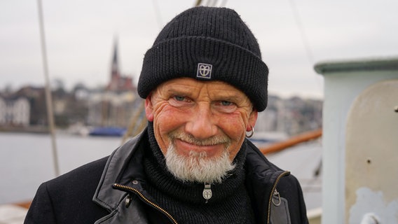 Sänger und Santiano-Bandmitglied Björn Both steht auf einem Segelschiff und lächelt in die Kamera. © NDR 
