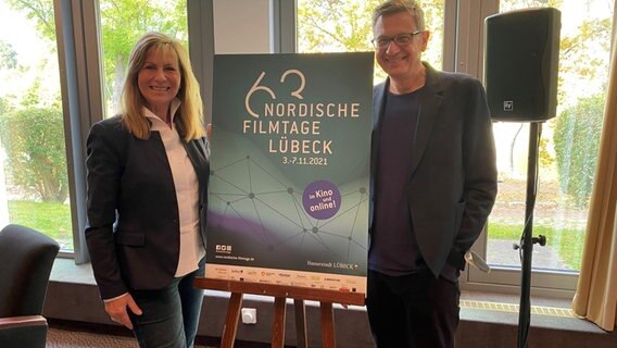 Geschäftsführerin Susanne Kasimir steht links im Bild, rechts neben ihr ein Plakat von den Nordischen Filmtagen und rechts daneben steht der künstlerische Leiter der Nordischen Filmtage Thomas Hailer. © NDR Foto: Linda Ebener
