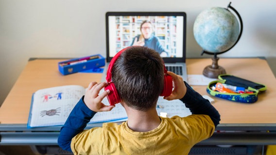 Online-Unterricht: Ein Junge sitzt an seinem Schreibtisch und hört seinem Lehrer über den Laptop zu. © imago 