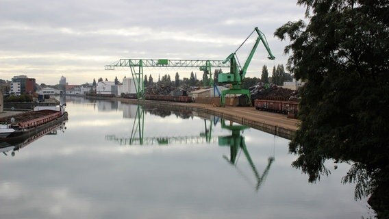 Zu sehen ist der Osnabrücker Hafen. In der Mitte ist Wasser und rechts steht ein grüner Kran. © NDR.de Foto: Claus Halstrup