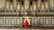 Eine Frau in roter Jacke sitzt an einer Orgel. © imageBROKER/Raimund Kutter via w 