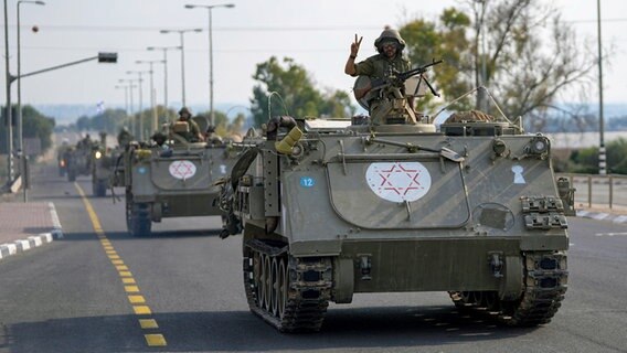 Ein israelischer Soldat zeigt das Victory-Zeichen von einem gepanzerten Mannschaftstransportwagen aus, der sich im Süden Israels auf die Grenze zum Gazastreifen zubewegt © Ohad Zwigenberg/AP/dpa 