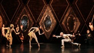 Verschiedene Darsteller des Balletts "Petruschka / Der Feuervogel" tanzen in zwei Gruppen, die sich gegenüberstehen, auf einer Bühne. © Admill Kuyler 