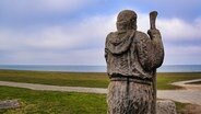 Eine Mönchsfigur in Puttgarden (Fehmarn), am Horizont das Meer © picture alliance / Zoonar Foto: HGVorndran