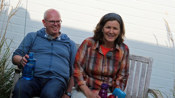 Klaas Grensemann und Heike Götz sitzen lachend auf einer Bank  Foto: Annkathrin Bornholdt