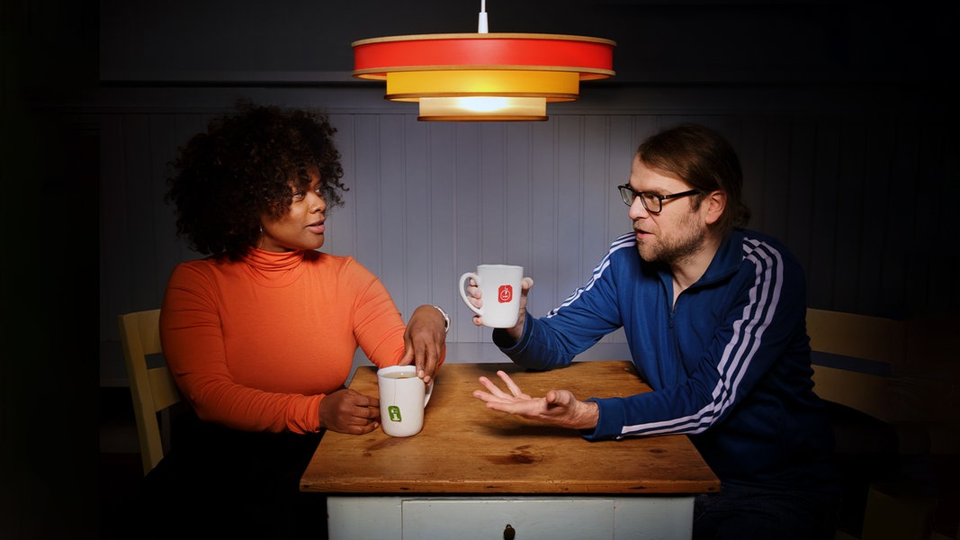 Mann und Frau sitzen am Tisch und trinken Tee.