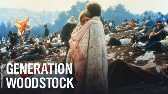 Menschen beim Woodstock Festival 1969, im Vordergrund umarmt sich ein Paar. © picture alliance/United Archives Foto: TBM