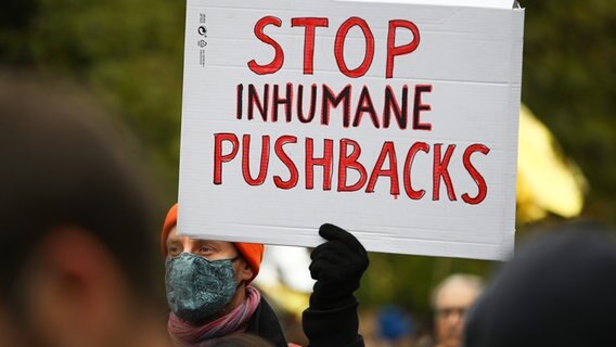Ein Mann hält ein Plakat in die Luft, auf dem "STOP INHUMANE PUSHBACKS" steht. © picture alliance / NurPhoto / STR 
