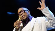 Quincy Jones spricht in ein Mikrofon und hält einen Arm hoch. © Dominic Favre/KEYSTONE/dpa 