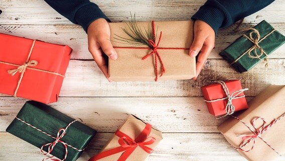 Hände halten ein weihnachtlich dekoriertes Paket. © Fotolia.com Foto: jakkapan