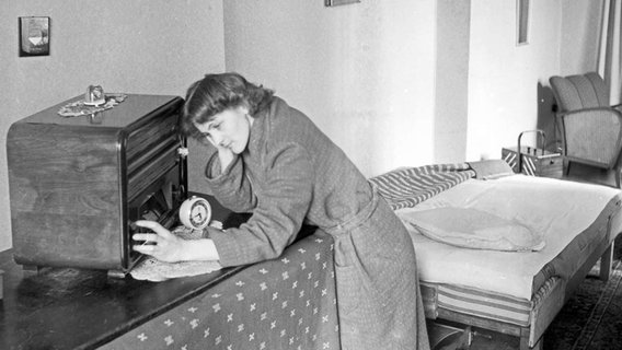 Eine junge Frau hängt in den 50er-Jahren gebannt an ihrem Radio. © picture alliance/United Archives Foto: Siegfried Pilz