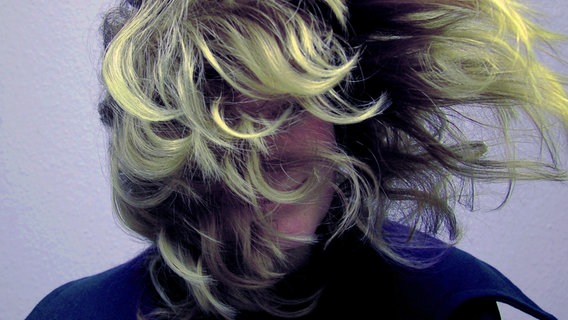 Eine blonde Frau mit langem, welligem Haar wirft diese von der linken Seite kommend vor ihr Gesicht. © elsone / photocase.de Foto: elsone